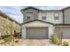 Inviting townhome with a two-car garage, stone accents, and lush landscaping, providing a comfortable and stylish living space at 712 Monroe Hill Pl, Henderson, NV 89011