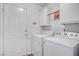 Functional laundry room featuring modern washer and dryer units, cabinet storage and convenient access to an exterior door at 3581 Pahrump Valley Blvd, Pahrump, NV 89048