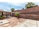 The backyard features gravel landscaping, a covered patio area, and a tall brick wall for privacy at 436 Pumpkin Way, Henderson, NV 89015