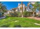 Beautifully landscaped condo exterior with lush green lawn and mature landscaping around the building at 5412 Harmony Green Dr # 101, Las Vegas, NV 89149