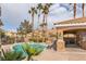 Community pool area with lush landscaping, covered seating, and grilling area under a bright, partly cloudy sky at 6790 Gold Yarrow St, Las Vegas, NV 89148