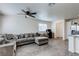 Spacious living room featuring modern gray sofa, ceiling fan, and wood-look flooring, bathed in natural light at 6804 Surf Green Ct, North Las Vegas, NV 89086