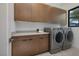 Modern laundry room with front load machines and custom cabinets, with a bright window at 794 Willits St, Las Vegas, NV 89138