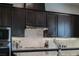 A kitchen with tile backsplash, granite countertop, stainless steel appliances, and dark wood cabinets at 8245 Broad Branch Way, Las Vegas, NV 89113