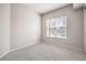 A small carpeted bedroom with a large window and neutral-colored walls at 50 E Serene Ave # 107, Las Vegas, NV 89123