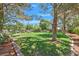 Expansive backyard featuring lush green grass, mature trees, and a charming pergola, perfect for outdoor enjoyment at 8208 Flowing Rapids Ct, Las Vegas, NV 89131