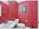 Powder room displaying a red wall, round mirror and white sink at 8208 Flowing Rapids Ct, Las Vegas, NV 89131