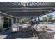 Luxurious outdoor kitchen and pizza oven under a modern pergola with a view of the sparkling pool at 8637 Home Gate Ct, Las Vegas, NV 89113
