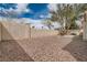 Enclosed backyard area with neutral colored stone landscaping, tall walls and shade tree at 9532 Calico Garden Ave, Las Vegas, NV 89134