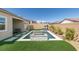 Backyard featuring a pool, spa, fire pit, artificial grass and lush landscaping at 9974 Petroglyph Canyon Ave, Las Vegas, NV 89166