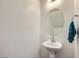 Clean half-bathroom featuring a pedestal sink, a round mirror, and a towel rack at 10663 Sariah Skye Ave, Las Vegas, NV 89166