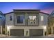 Modern townhome featuring gray exterior, two private balconies, awnings, and an attached two-car garage at 11315 Gravitation Dr, Las Vegas, NV 89135