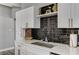 Modern kitchen featuring white cabinets, a quartz countertop, and a black tile backsplash at 1660 Izabella Ave, Las Vegas, NV 89169