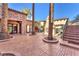 Beautiful courtyard featuring patterned pavers, mature palm trees, and a decorative outdoor fireplace at 1795 Anelli Ct, Henderson, NV 89012