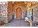 An ornate wooden door framed in stone, stone tile entry, and bench with a small fountain feature at 1795 Anelli Ct, Henderson, NV 89012