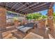 Relaxing outdoor kitchen features a pergola, stone counters and bar, with seating and a modern barbecue at 1795 Anelli Ct, Henderson, NV 89012