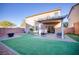 Fenced backyard with artificial grass, stone pavers, a covered patio, and desert landscaping at 189 Kings Canyon Court Ct, Henderson, NV 89012