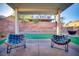 Covered patio with two chairs overlooking the backyard with artificial grass and a retaining wall at 189 Kings Canyon Court Ct, Henderson, NV 89012