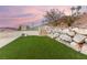 Backyard featuring a grassy area with desert landscaping and rock terracing at 211 Granite Ct, Boulder City, NV 89005