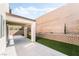 A covered patio extends to an artificial lawn, complemented by a high privacy wall, creating a serene outdoor space at 2482 Denholme St, Henderson, NV 89044