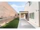 A covered patio leads to the artificial turf and a tall retaining wall, offering a private and low-maintenance outdoor retreat at 2482 Denholme St, Henderson, NV 89044