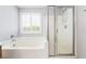 Bathroom showcasing soaking tub with window and a separate glass-enclosed shower at 2482 Denholme St, Henderson, NV 89044