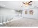 Upstairs loft area featuring neutral carpeting, a ceiling fan, and staircase railing, offering a flexible living space at 2482 Denholme St, Henderson, NV 89044