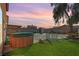 Backyard showcasing a hot tub, manicured lawn, shed, and mature tree against a dusk sky at 3193 Emerald Creek Dr, Las Vegas, NV 89156