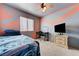 Modern bedroom with orange and gray walls, desk, TV, and a comfy blue bed at 3193 Emerald Creek Dr, Las Vegas, NV 89156