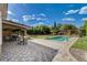 Expansive backyard showcasing a covered patio, lush green lawn, mature trees, and a sparkling blue swimming pool at 3518 W Agate Ave, Las Vegas, NV 89139