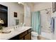 Well-lit bathroom features a shower-tub combo, single sink vanity with neutral countertop and cabinet, and a decorative mirror at 3518 W Agate Ave, Las Vegas, NV 89139