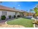 Well-manicured backyard with an artificial lawn, stone accents, a covered patio, and a built-in grill area at 5437 Escallonia St, Las Vegas, NV 89149