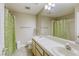 Bathroom featuring double sinks, neutral cabinets, and a green leaf patterned shower curtain at 5437 Escallonia St, Las Vegas, NV 89149