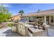 Outdoor kitchen with a built in grill, mini fridge, tile countertops, and desert landscaping at 5437 Escallonia St, Las Vegas, NV 89149