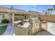 Outdoor kitchen with a grill, mini fridge, tile countertops, statues, and desert landscaping at 5437 Escallonia St, Las Vegas, NV 89149