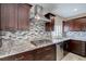 A kitchen with granite countertops, mosaic backsplash, stainless steel appliances, and dark brown cabinets at 7905 Coral Point Ave, Las Vegas, NV 89128