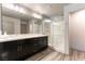 Modern bathroom with double sinks, dark cabinets, a large mirror, and a glass-enclosed shower with marble-look tile at 8179 Shale Canyon St, Las Vegas, NV 89139
