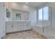 Bright bathroom with double vanity, large mirror, soaking tub, and glass-enclosed shower at 844 Aurelie Ridge St, Henderson, NV 89011