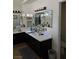 Bathroom with dual sinks, large mirror and dark wood cabinets at 853 Rusty Anchor Way, Henderson, NV 89002