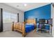 Bright bedroom featuring a wood bed frame, blue accent wall, and a desk at 9144 Irish Elk Ave, Las Vegas, NV 89149