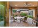 Inviting outdoor patio with cozy seating area, ceiling fan, and manicured landscaping at 9889 Gemstone Sunset Ave, Las Vegas, NV 89148