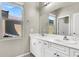 Bright bathroom with double vanity and a large mirror reflecting natural light from the window at 10529 Mount Blackburn Ave, Las Vegas, NV 89166