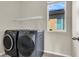 Laundry room with front loading washer/dryer, shelving, and a window at 10529 Mount Blackburn Ave, Las Vegas, NV 89166