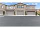 Attached garages of a residential townhome with shrubbery and light-colored stucco at 11408 Newton Commons Dr # 104, Las Vegas, NV 89135