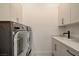 Modern laundry room featuring a front-load washer, dryer, sink and storage cabinets at 12199 Canyon Sunset St, Las Vegas, NV 89138