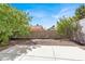 Backyard with concrete patio, mature trees, and block wall at 1405 Sycamore Spring Ct, Las Vegas, NV 89128