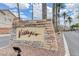 Community entrance sign with stone accents, set against a backdrop of palm trees and community buildings at 1881 W Alexander Rd # 1135, North Las Vegas, NV 89032