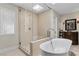 Bright bathroom with glass-enclosed shower, soaking tub, and a decorative cabinet at 3010 La Mesa Dr, Henderson, NV 89014