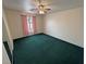 This bedroom has green carpet, a ceiling fan, and a window with pink curtains at 3580 Unicorn Ave, Pahrump, NV 89048