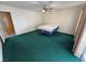 This bedroom has green carpet, a ceiling fan, and sliding glass doors to the backyard at 3580 Unicorn Ave, Pahrump, NV 89048